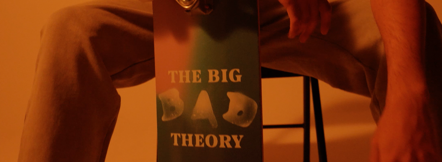 Person holding a skateboard with 'The Big Bang Theory' text against a warm-toned background